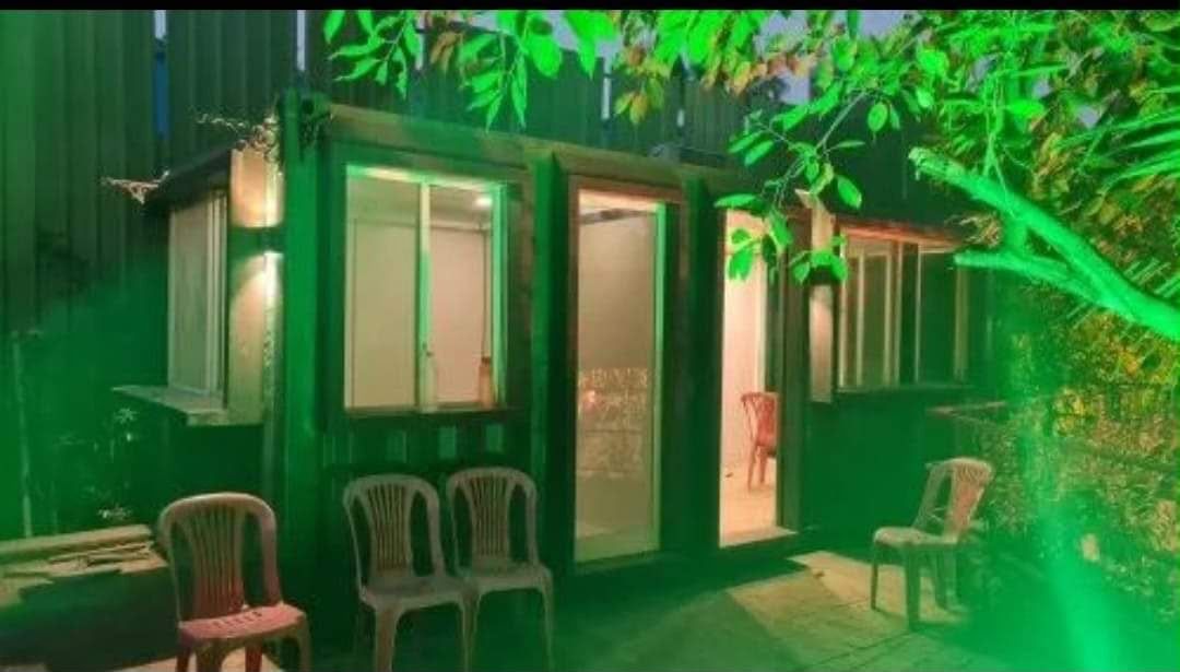 Container bungalow lit up at night, with bay windows and glazed entrance